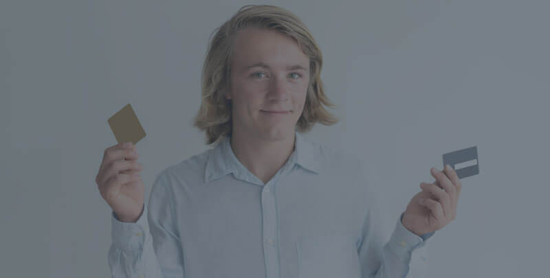 A man with blonde hair holding two credit cards.