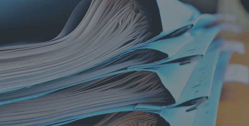 A stack of papers in blue folders.