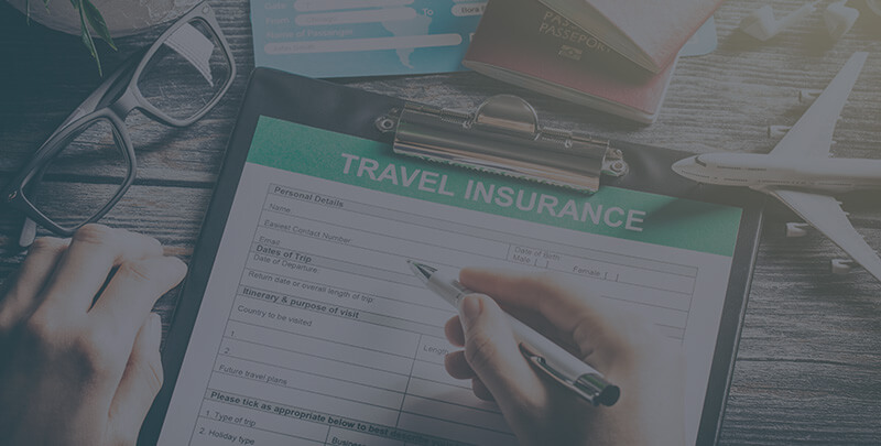 A clipboard with a travel insurance document on a desk.