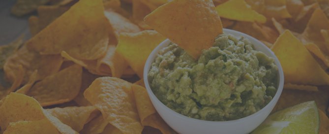 Several chips surrounding a bowl of guacamole.