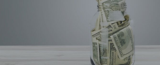 A clear jar of money on a table.