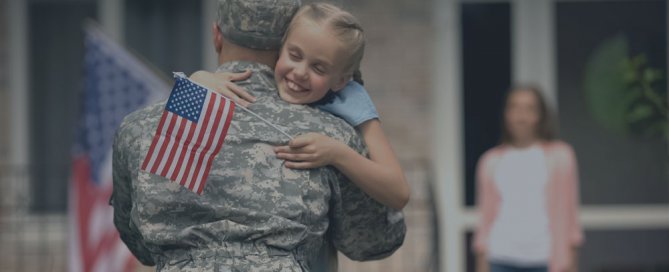 A military man hugging a young girl.