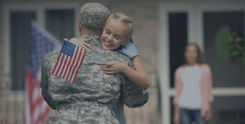 A military man hugging a young girl.