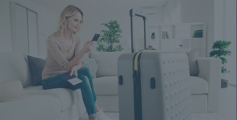 A woman sitting on a white couch with her suitcase.