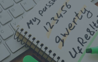 A notepad with password laying on top of a keyboard.