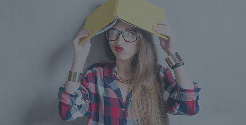 A girl wearing glasses with a yellow book on her head.