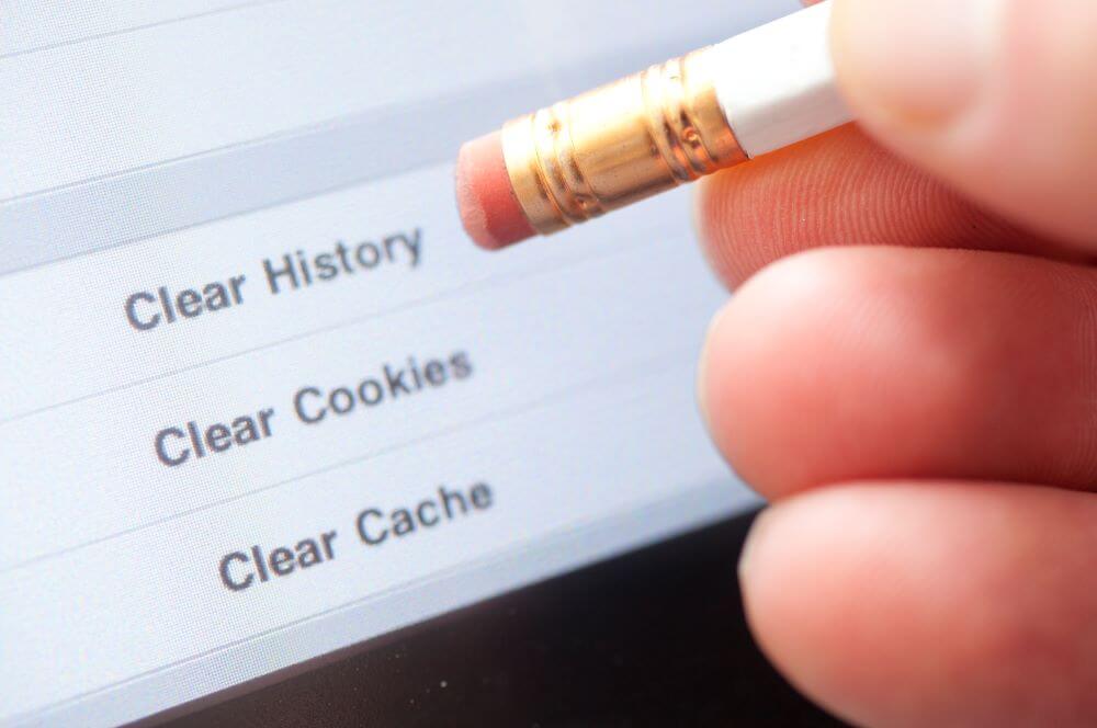 A person holding a pencil to clear cookies on computer.