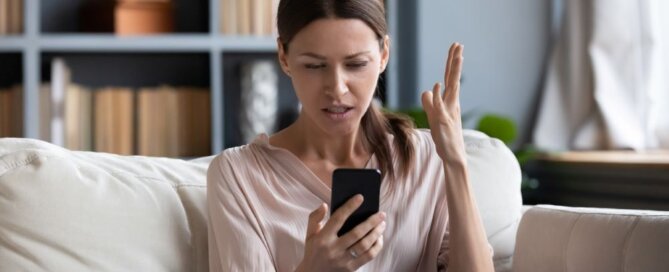 Confused angry young woman having problem with phone.