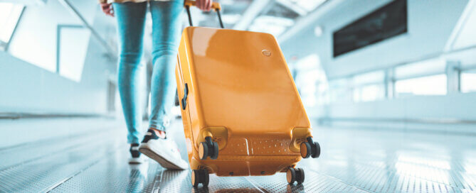 Female traveler walking with a yellow suitcase at the airport terminal