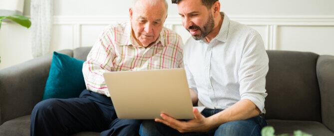 Happy son and elderly father using the laptop together