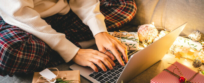 Close up of woman hands with gifts, typing at laptop.