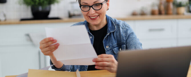 woman smiling as she reads a piece of paper.