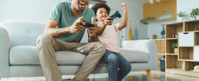 Father and son playing video games on couch