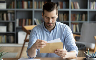 Man sitting at desk holding an envelope