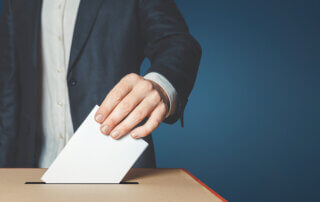 Male voter holds in his hand a ballot above the ballot box