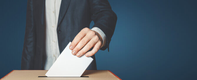 Male voter holds in his hand a ballot above the ballot box