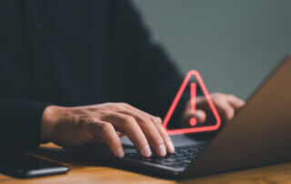 person using computer laptop with triangle caution warning sign for notification error